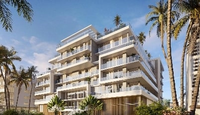 A mid-rise condo surrounded by palms and shot at a slight upward angle